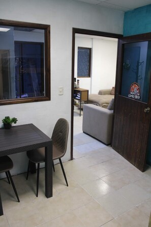Una habitación con una mesa de comedor, sillas, un sofá y una puerta con una pegatina.