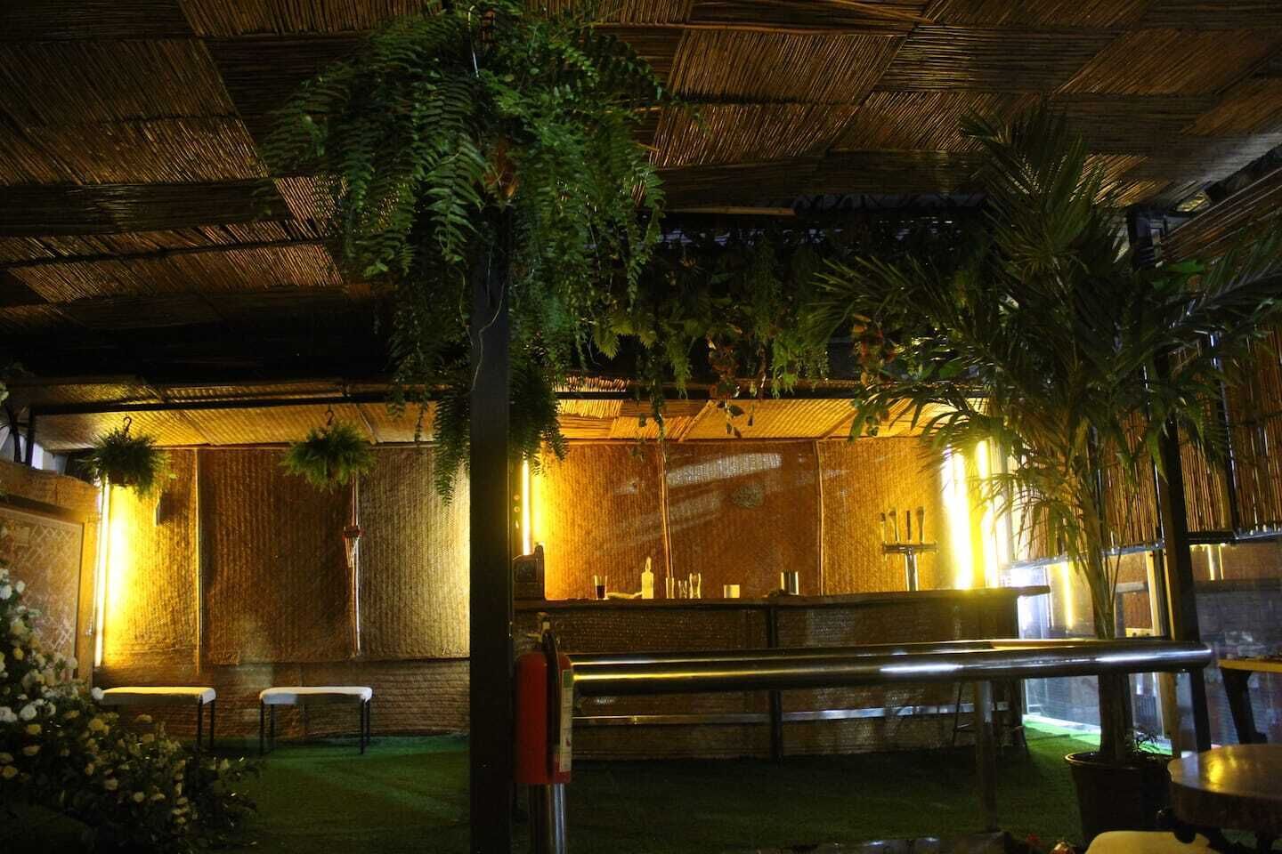 An indoor space with a thatched roof, wooden walls, and a seating area with tables and chairs.