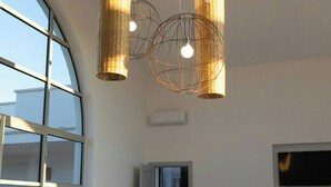 Um interior moderno com uma grande janela em arco, um sofá com almofadas e uma TV de tela plana fixada na parede.