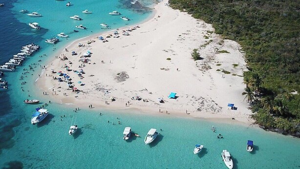 Luftaufnahme eines Strandes mit Booten, Sandstrand und dichter Vegetation.