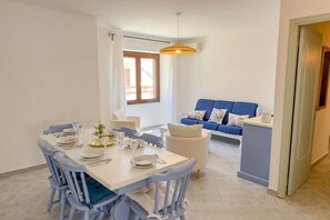 Un'area pranzo con tavolo apparecchiato per quattro persone, un divano blu e un angolo cottura.