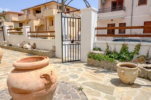 Un cortile con vasi in terracotta, un cancello e edifici con balconi.