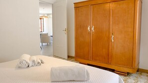 Et hotelværelse med en seng, et træskab og et badeværelse i baggrunden.