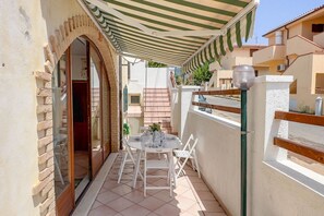 Un patio techado al aire libre con una mesa y sillas, una cerca de madera y un edificio al fondo.