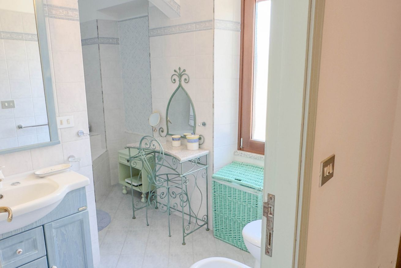 A bathroom with a sink, mirror, vanity, and a green basket.