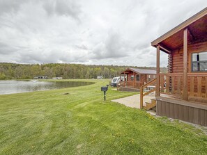 A lakeside cabin with a deck, a picnic table, and a view of the lake and forest.