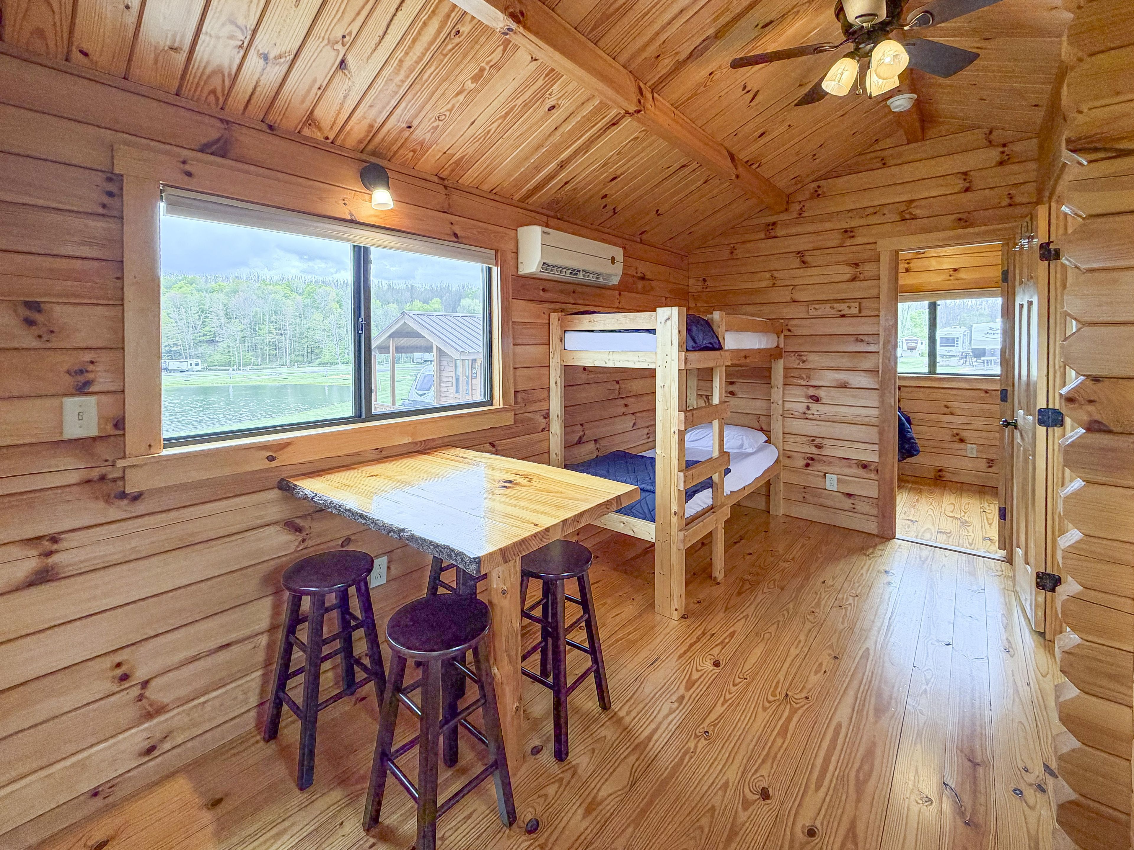 Eine Hütte mit Etagenbetten, einem Tisch und Barhocker.