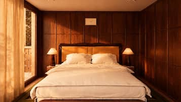 A hotel room with a large bed, wooden paneling, two bedside lamps, and a window with curtains.