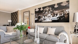 Ein modernes Wohnzimmer mit einem grauen Sofa, einem Glastisch und einem großen Schwarz-Weiß-Foto an der Wand.
