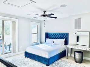Un dormitorio con una cama, ventilador de techo, ventana y escritorio con silla.