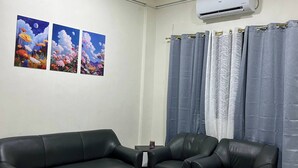 A living room with a black leather sofa, a coffee table, and a wall-mounted air conditioner. - Jaz Urban Stay - 337f (Angeles City)