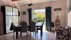 Ein Essbereich mit Tisch, Stühlen, einem Schrank und Blick ins Freie.
