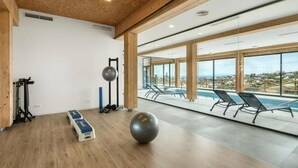 Un gimnàs amb equip d'exercici, una pilota gran i vista a una piscina.