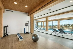 Un gimnasio con equipo de ejercicio, una pelota de ejercicios grande y vistas a una piscina.