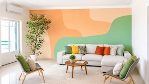 Ein modernes Wohnzimmer mit einer Couch, zwei Sesseln, einem Couchtisch und einer großen Pflanze in einem Topf.