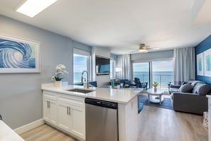 Eine moderne Küche mit Geschirrspüler, ein Essbereich mit Tisch und Stühlen, eine Sitzecke und Blick aufs Meer.