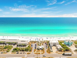 A coastal hotel with a parking lot, beach view, and a mix of modern and traditional architecture. - Sea Clearly | Close to Beach | Golf Cart (LSV) | 4 Bikes | Pool (Santa Rosa Beach)