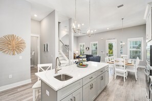 A modern kitchen with a central island, white cabinetry, and pendant lighting. - Sea Clearly | Close to Beach | Golf Cart (LSV) | 4 Bikes | Pool (Santa Rosa Beach)