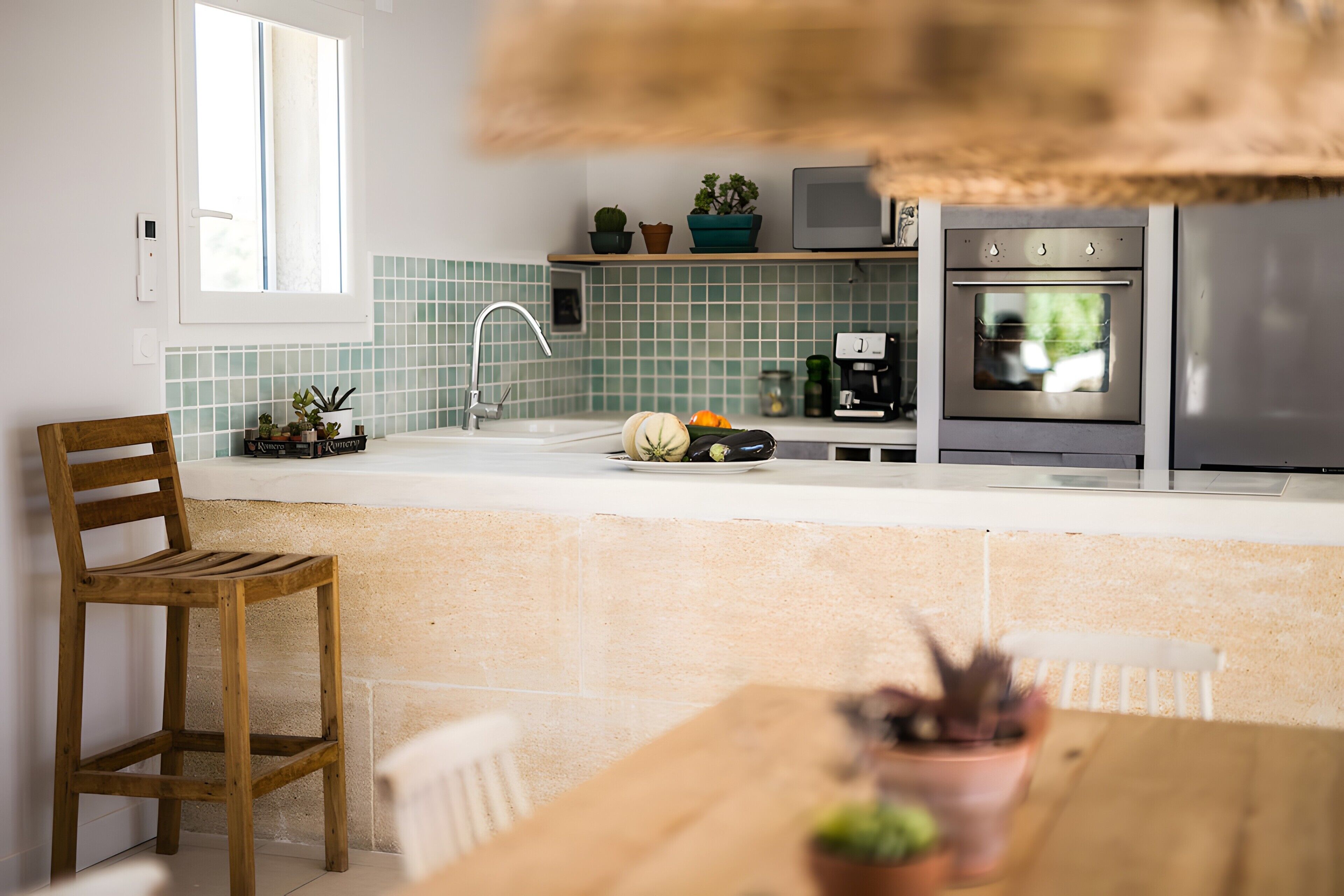Una cocina con una silla de madera, una mesa de comedor, un fregadero, una estufa y una ventana.