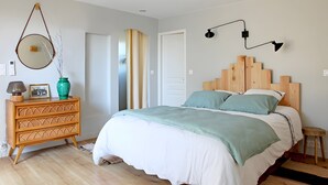 Un dormitorio con cama, cómoda, espejo y lámparas fijadas a la pared.