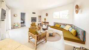 Una sala de estar moderna con un sofá, sillas, una mesa de centro y una televisión.