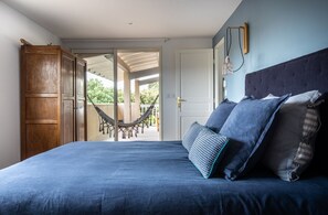 Un dormitorio con cama, almohadas, una hamaca y vistas al exterior.