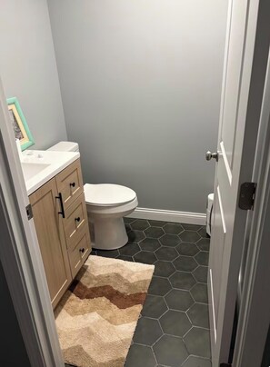 Ein Badezimmer mit Toilette, Waschbecken, einem Schrank und einem sechseckig gefliesten Boden.