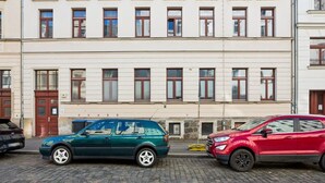 Una calle con dos coches aparcados y un edificio con varias ventanas y puertas.