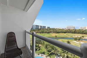 Ein Balkon mit Blick auf einen Golfplatz, Palmen und moderne Gebäude.