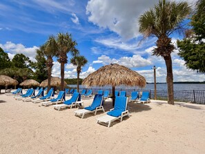 A beach with rows of sun loungers and thatched umbrellas. - Disney Area 3BR Condo Pickleball, Pools & Free WiFi (Davenport)
