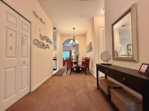 A hallway with a dining area, a black console table with a mirror, and a carpeted floor. - Disney Area 3BR Condo Pickleball, Pools & Free WiFi (Davenport)