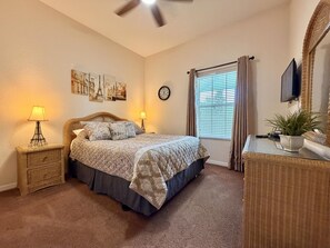A bedroom with a bed, two bedside lamps, a clock, a window with curtains, a television, and a potted plant. - Disney Area 3BR Condo Pickleball, Pools & Free WiFi (Davenport)