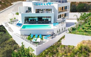 Un immeuble moderne à plusieurs étages, doté d’une piscine sur le toit, d’un espace extérieur aménagé et d’un jardin paysager.