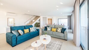 A modern living room with two sofas, a coffee table, and a staircase leading to another level. - Villa Albert, Pool, Jacuzzi, Games Room (Armação de Pêra)