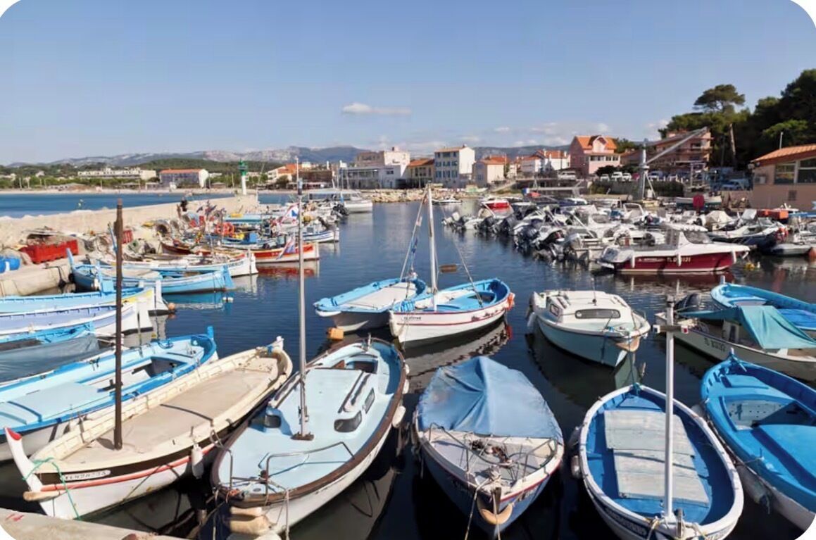 Un port de plaisance où sont amarrés différents types de bateaux, un ciel dégagé et des bâtiments en arrière-plan.