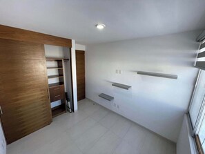 Ein Zimmer mit einem Holzkleiderschrank, einer Heizung und einem weiß gefliesten Boden.