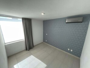 Ein Zimmer mit einem großen Fenster, grauen Vorhängen, einer Wand mit Muster und einer Klimaanlage.