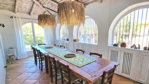 A dining area with a wooden table, chairs, and hanging rattan chandeliers. - Villa Cala Sassari - A refined Sardinian villa for families and groups (Sassari)