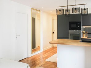 Une cuisine moderne dotée d’un plan de travail en bois, d’appareils électroménagers en acier inoxydable et de luminaires suspendus.