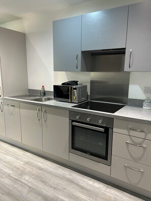 Una cucina moderna con elettrodomestici in acciaio inossidabile, mobili grigi e pavimento in legno.