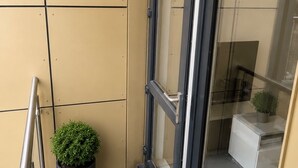 Ein kleiner Balkon mit einem Topfpflanzen, einer Glastür und einem Metallgeländer.
