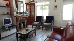 Una sala de estar con televisión, chimenea, dos sillones, un sofá y una mesa de centro.