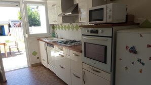 Una cocina con armarios blancos, estufa a gas, microondas y refrigerador.