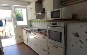 Eine Küche mit weißen Schränken, einem Gasherd, einer Mikrowelle und einem Kühlschrank.