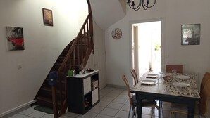 Comedor con una mesa dispuesta para dos, una escalera y una puerta que da al exterior.
