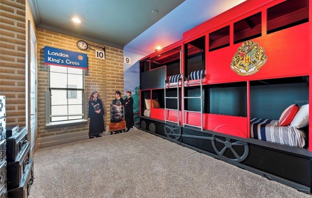 Una habitación con una cama litera roja, un cartel de London King's Cross y un reloj en la pared.