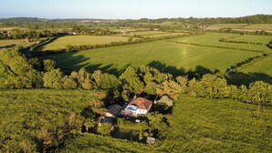 Vista aérea de una propiedad rural con una casa rodeada de campos y árboles.