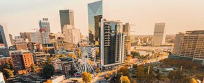 Paisagem urbana com edifícios modernos e altos, uma roda-gigante em destaque, e uma combinação de estruturas comerciais e residenciais.