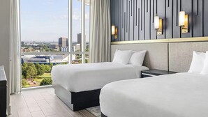 Een hotelkamer met twee bedden, een groot raam met uitzicht op de stad en een modern wandontwerp.