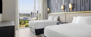 Ein Hotelzimmer mit zwei Betten, einem großen Fenster und Stadtblick sowie einem modernen Wanddesign.